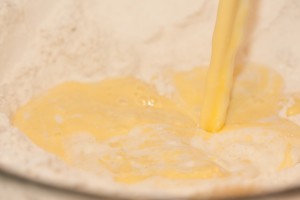 Pouring melted margarine and milk into flour