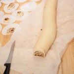 Cutting up the rolled up dough into cinnamon whirls