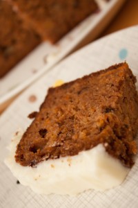 A slice of Carrot, Orange, and Walnut Sponge Cake on a plate, with the cake in the background