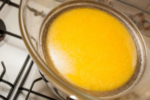 Home-made lemon curd in a glass bowl on top of a saucepan. At this stage the margarine has melted but the mixture has yet to thicken.