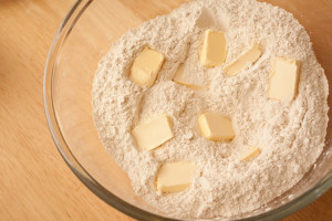 Glass bowl with flour and pieces of margarine.