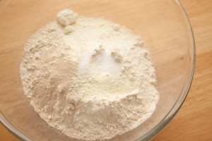 Flour, fast action yeast, salt, and dried milk powder in a glass bowl before mixing.