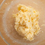 Creamed butter and sugar with egg mixed in. The mixture is in a glass bowl on a wooden surface.